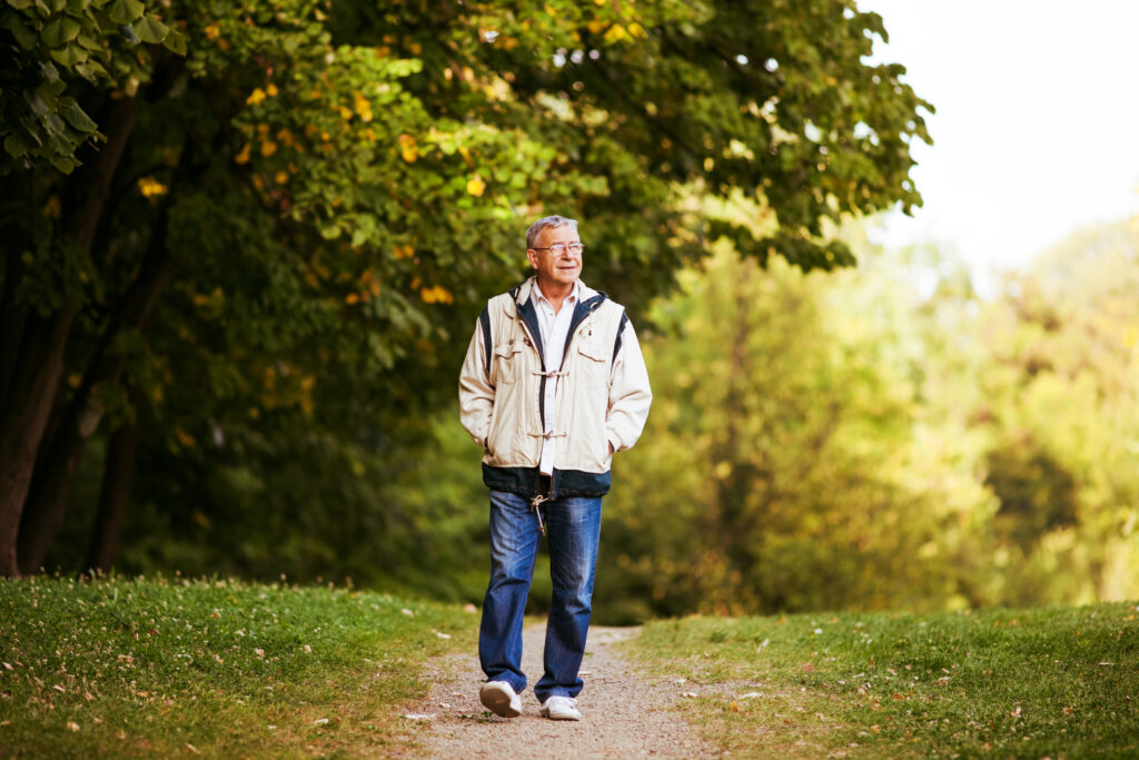 Happy senior man walking and relaxing in park